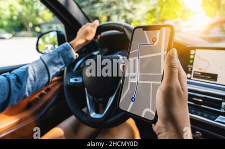 Tourist using GPS map navigation app on smartphone screen to get direction to destination address in the car, travel and technology concept image Stock Photo