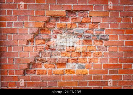 Old red brick wall with shattered center close up. Grunge texture and background Stock Photo