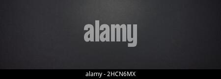 dark black paper background texture or backdrop, banner size, with copyspace for your individual text. Stock Photo
