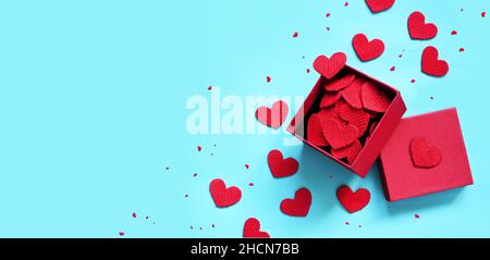 Open gift box and knitted hearts on blue background, top view. Valentines day greeting card. Flat lay style. Stock Photo