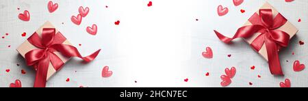 Top view photo of valentine's day decorations white gift boxes with red ribbon bow and small hearts on isolated light background with empty space. Stock Photo