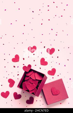 Open gift box and knitted hearts on pink background, top view. Valentines day greeting card. Flat lay style. Stock Photo