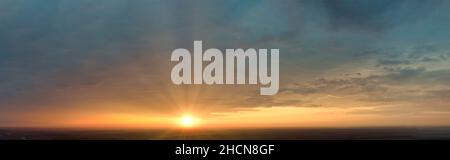 Sunrise with sunbeams from behind the clouds. Panorama of the morning sky with colorful clouds in the sky Stock Photo