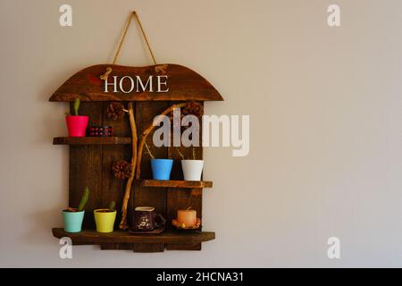 Wooden decorative object with colored flowerpots and pine cones hanged on wall Stock Photo