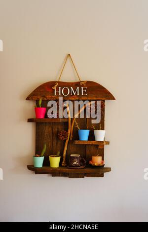 Wooden decorative object with colored flowerpots and pine cones hanged on wall Stock Photo