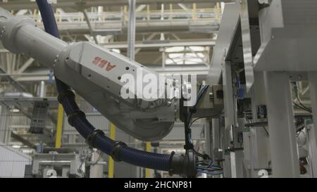 Close up of automatic robotic arm inserting detail into the mechanism at the production line of a car factory. Professional equipment and machinery co Stock Photo