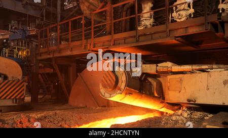 Hot metal production at the factory, metallurgy concept. Molten steel flowing in metallurgical chute, heavy industry. Stock Photo