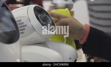 Russia, Moscow - 25 August 2018: People playing with humanoid robot during international technology exhibition. Imitation of emotions in the robot dur Stock Photo