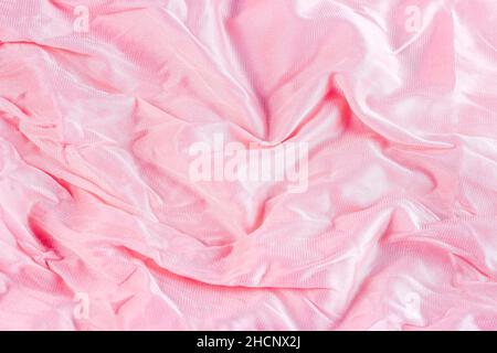 Light pastel pink color wavy nylon and polyamide textile pattern as a smooth textured background. Pale rose colored soft fabric drapery. Stock Photo