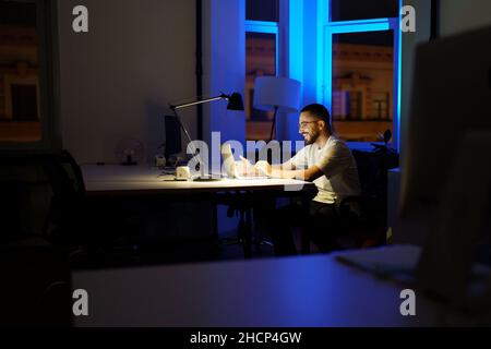 Young businessman has video conference call with colleague, partners work late in office on covid-19 Stock Photo