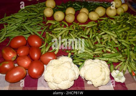 Fresh homegrown Organic raw vegetables at home. Many Vegetables like tomato, lemons, cauliflower, beans and green chillies washed and dried on cloth f Stock Photo