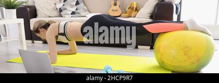 Young athletic woman doing plank on fitball at home Stock Photo