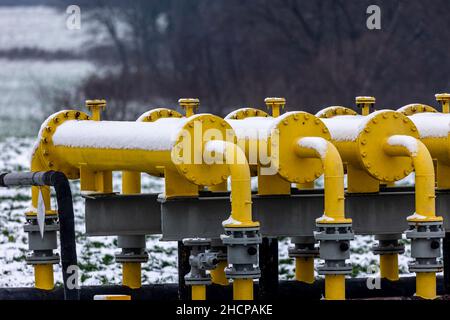 Yellow gas infrastructure elements sticking out of the ground. Winter photo of a snow-covered gas pipeline. High natural gas prices. The photo was tak Stock Photo