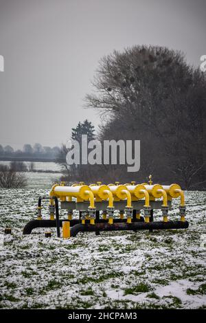 Yellow gas infrastructure elements sticking out of the ground. Winter photo of a snow-covered gas pipeline. High natural gas prices. The photo was tak Stock Photo