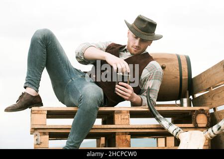 American cowboy man. Brutal western. Guy drinking whiskey. Stock Photo