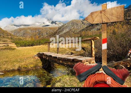Empty wooden directional sign with one arrow and mountaineering equipment in the National Park of Adamello Brenta. Trentino Alto Adige, Italy Stock Photo