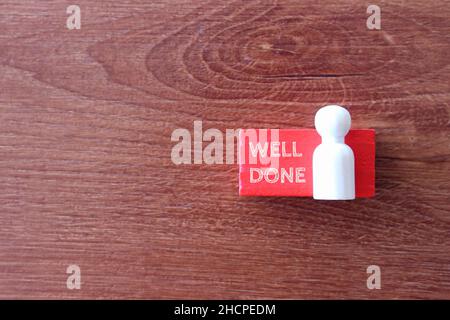 Top view of wooden doll with text WELL DONE. Copy space for text Stock Photo