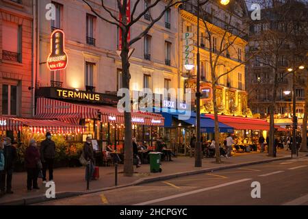 Paris, France - December 30, 2021 : View of a typical busy Parisian street with restaurants and bars at night time Stock Photo