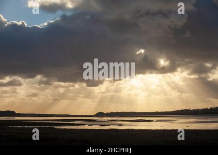 Shafts of sun ray light breaking through clouds at Malltraeth Anglesey, Wales Stock Photo