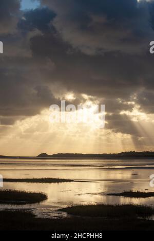 Shafts of sun ray light breaking through clouds at Malltraeth Anglesey, Wales Stock Photo