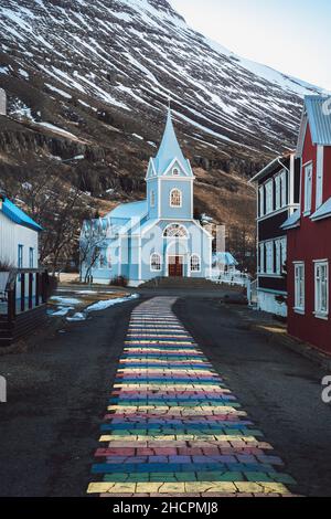 Rainbow stripes on pavement leading up to the Seydisfjordur Church in Iceland Stock Photo