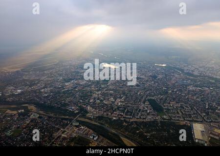 Aerial view from high altitude of distant city covered with puffy cumulus clouds forming before rainstorm in evening. Airplane point of view of cloudy Stock Photo