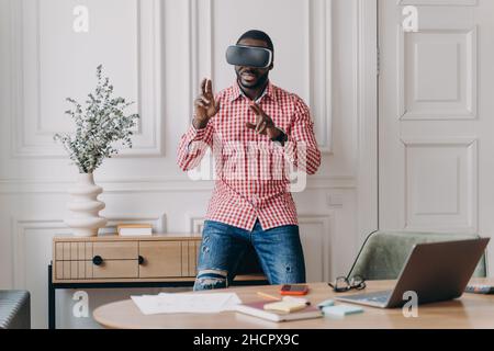 Young programmer or software developer African American man in VR headset glasses testing 3D games Stock Photo