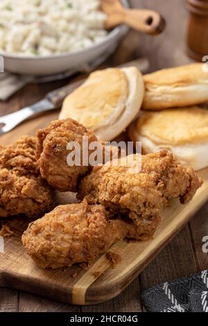 Cispy fried chicken leg and thigh dinner  with biscuits and mashed potatoes on a rustic wooden table Stock Photo