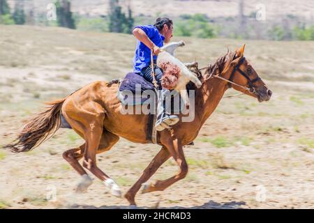 ISSYK KUL, KYRGYZSTAN - JULY 15, 2018: Player of kok boru, traditional horse game, with a goat carcass at the Ethnofestival Teskey Jeek at the coast o Stock Photo