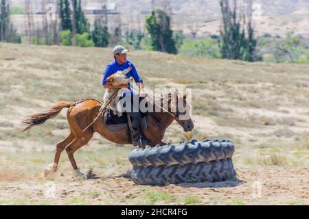 ISSYK KUL, KYRGYZSTAN - JULY 15, 2018: Player of kok boru, traditional horse game, with a goat carcass at the Ethnofestival Teskey Jeek at the coast o Stock Photo