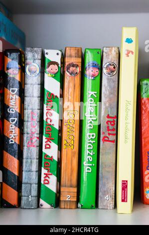 Row of Polish child books with different topics on a wooden shelf Stock Photo