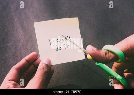 Hands cutting letter T with scissors with written text i can't do it. Business concept for determination Success Challenge self believe Motivation and Stock Photo
