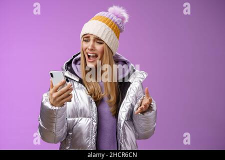 Bothered complaining dissatisfied cute blond girl yelling stupid smartphone standing unhappy recording audio message whining yelling mobile phone upse Stock Photo