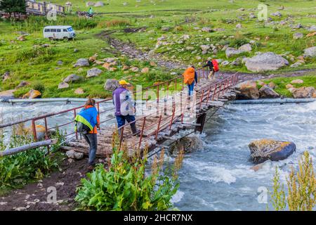ALTYN ARASHAN, KYRGYZSTAN - JULY 17, 2018: Foot bridge over Arashan river in the Terskey Alatau mountain range, Kyrgyzstan Stock Photo