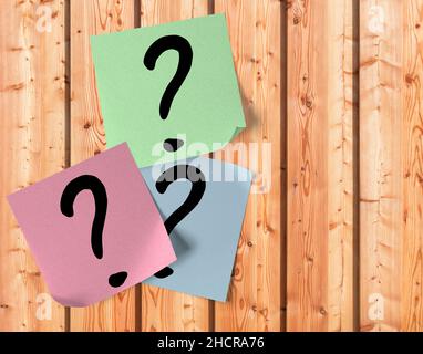 Sticky notes with question marks on a wooden wall Stock Photo
