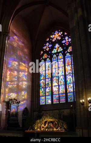 Europe, Czech Republic, Prague. St. Vitus's Cathedral at Chrismas. Thunov Chapel stained glass window & a nativity model. Stock Photo