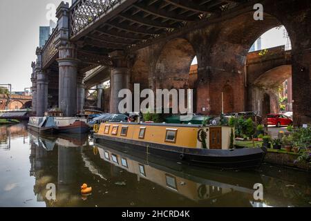 UK, England, Manchester, Castlefield, Bridgewater Canal basin, residential canal narrowboat below redundant railway viaduct Stock Photo
