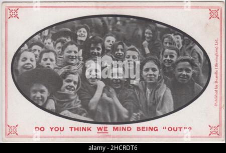 'Do you think we mind being 'out'?': postcard of young Lancastrian women, cotton mill workers who had been 'locked out' (i.e were on strike). Some are wearing shawls / head scarfs and all are smiling at the camera. The postcard was one of several on this subject published by Russells (Birmingham) Ltd. and may date from the 1912 'great lockout' in the Lancashire industry, the result of a dispute between the Cotton Spinners and Manufacturers Association and the Amalgamated Weavers Association