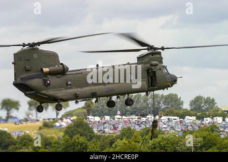 RAF, Royal Air Force Boeing Chinook HC2 tandem rotor helicopter ZD574 carrying out a winching demonstration at RIAT with campsite on Totterdown Hill Stock Photo