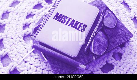 The word mistake word written on notepad, eye glasses and pen on crochet carpet. Education and business concept Stock Photo