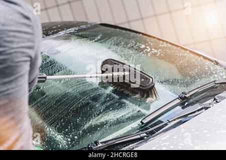 man washing his car with brush outdoors Stock Photo