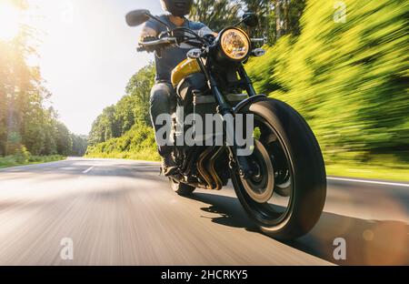 Motorcycle driver riding in Alpine highway at sunset Stock Photo