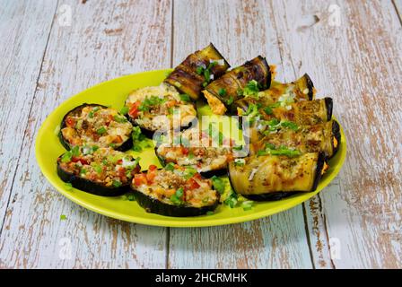 A festive snack of baked eggplant on a beautiful plate. Slices and rolls of vegetables with tasty filling. Stock Photo