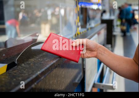 Faceless woman giving her passport at the airport check-in counter. Stock Photo