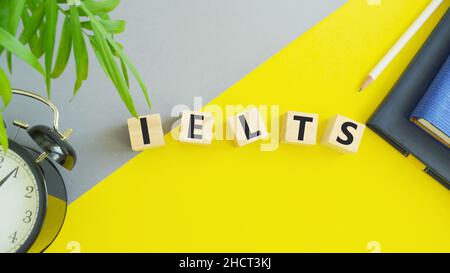 On wooden blocks under text: IELTS. IELTS words from wooden blocks with letters, International English Language Testing System IELTS exam concept. Stock Photo