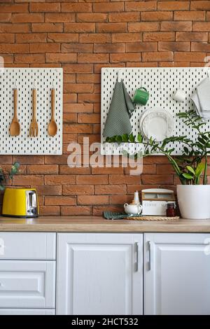 Peg boards with kitchenware hanging on brick wall Stock Photo