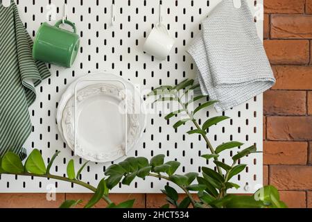 Peg board with kitchenware hanging on brick wall Stock Photo