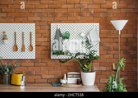 Peg boards with kitchenware hanging on brick wall Stock Photo