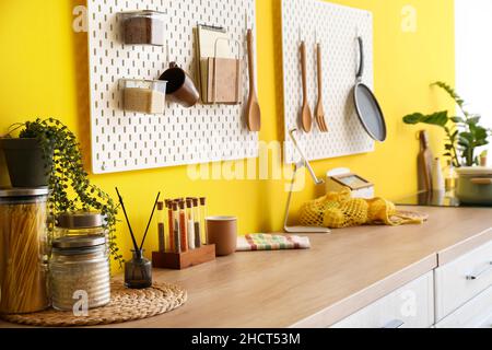 Peg boards with kitchenware hanging on yellow wall Stock Photo