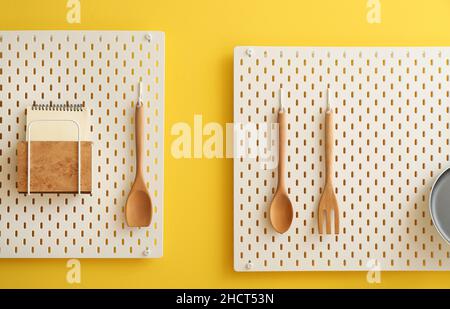 Peg boards with notebooks and spatulas hanging on yellow wall Stock Photo